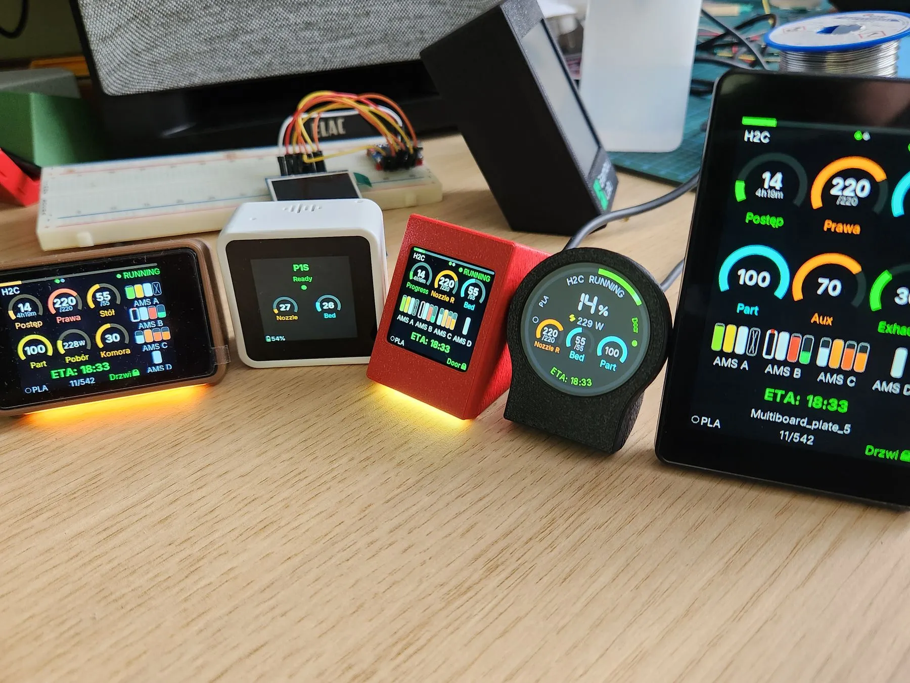 Five BambuHelper builds side by side on a desk, each showing the same print in progress
