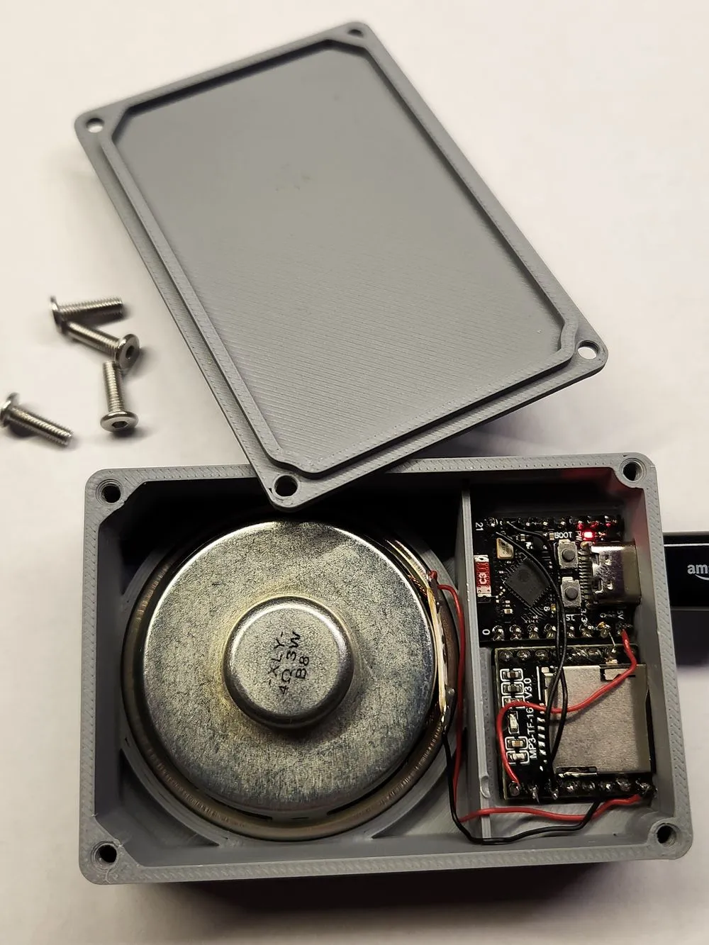 The doorbell opened up, showing the speaker, the ESP board and the DFPlayer module inside a printed case